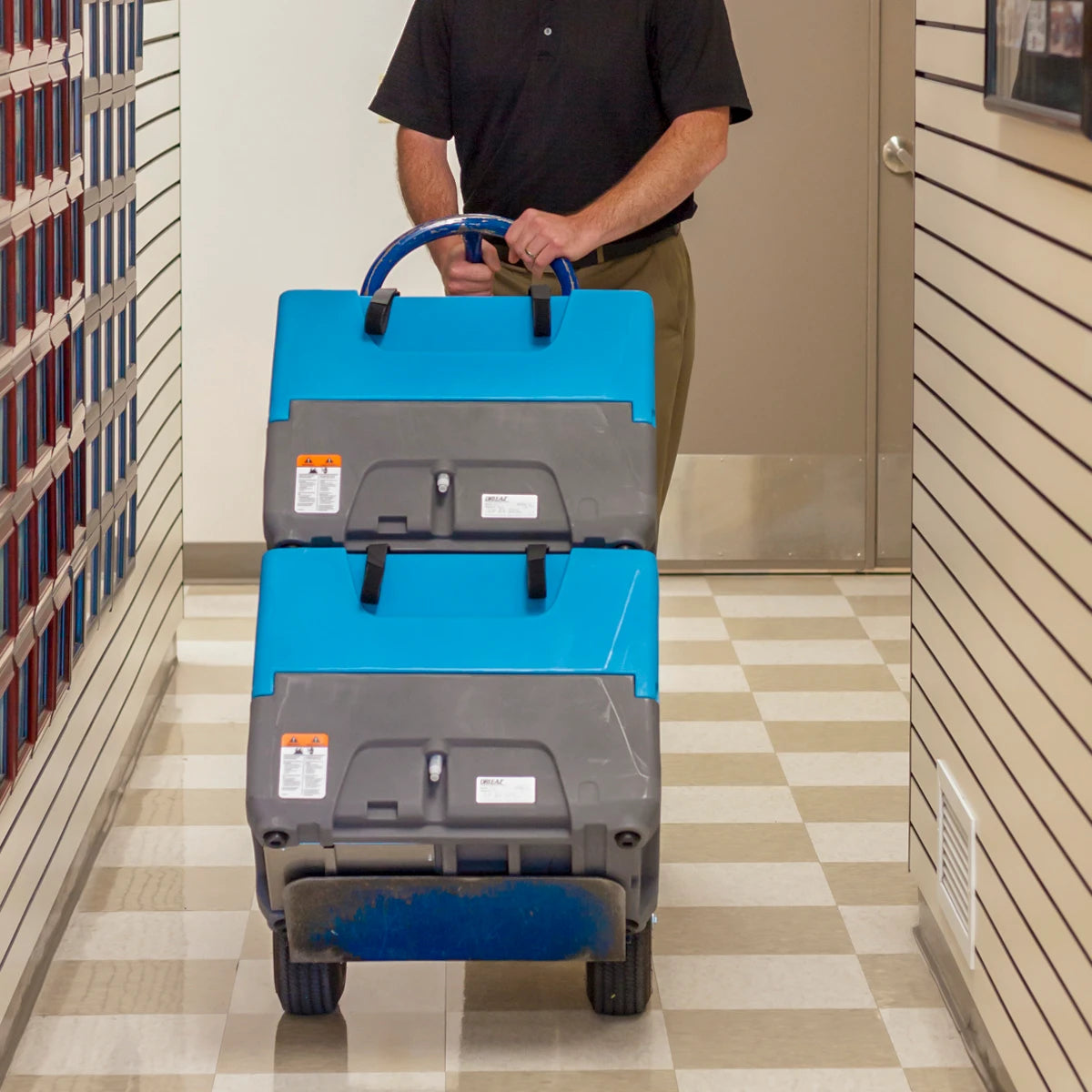 Technician transporting two stacked Dri-Eaz Revolution LGR Dehumidifiers through hallway