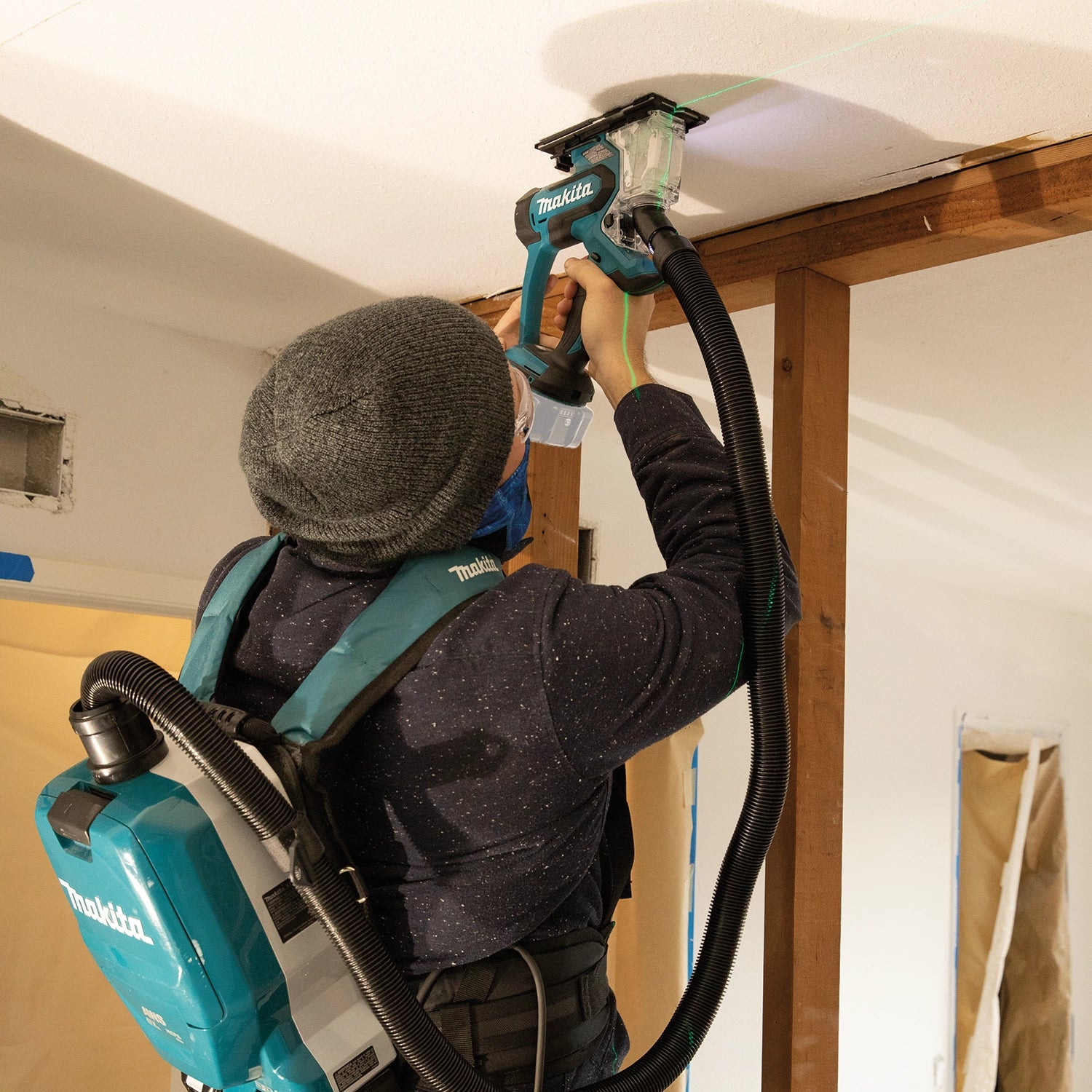 Makita saw cutting ceiling drywall while connected to vacuum