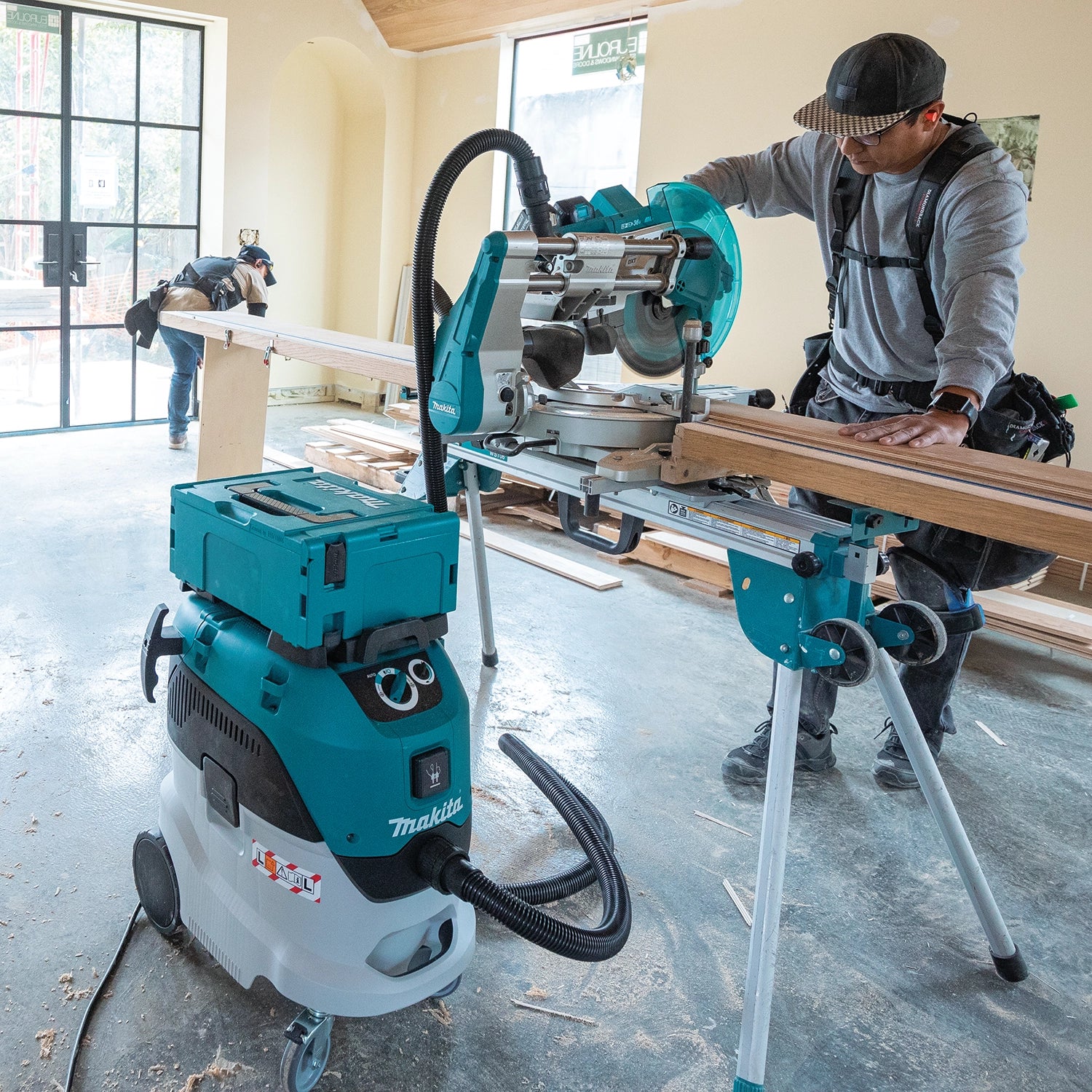 Contractor using a Makita miter saw connected to Makita VC4210L dust extractor on a residential jobsite
