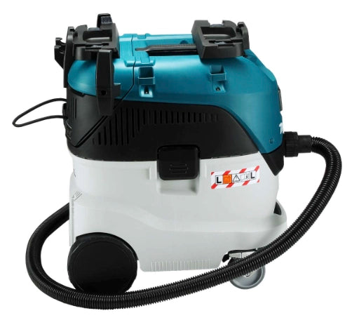 Side view of Makita VC4210L dust extractor with hose connected and caution label visible
