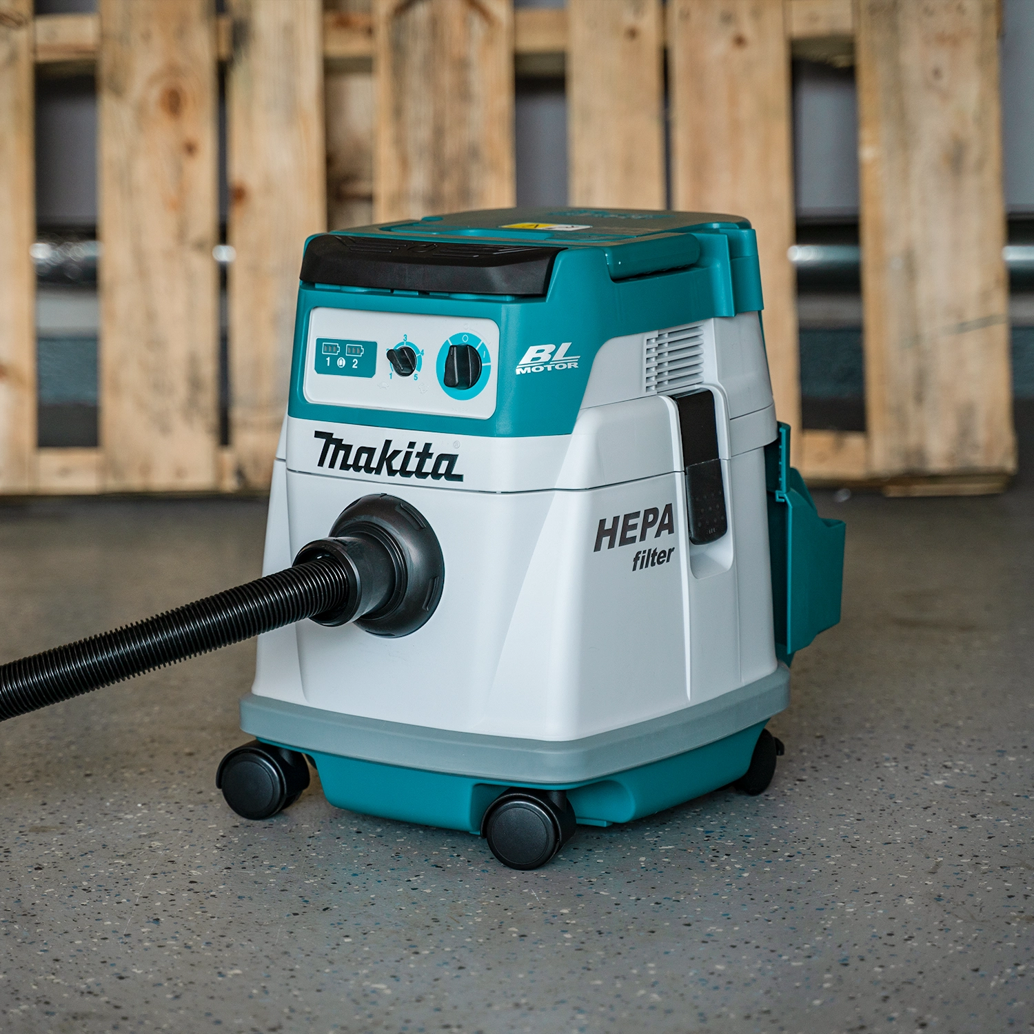 makita vacuum in use on site next to miter saw collecting fine dust