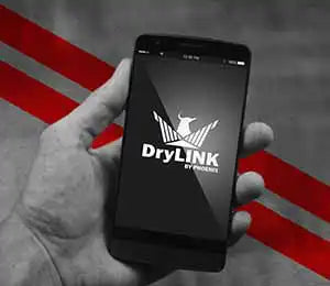 Hand holding smartphone displaying Phoenix DryLINK app used for remote monitoring of dehumidifier performance