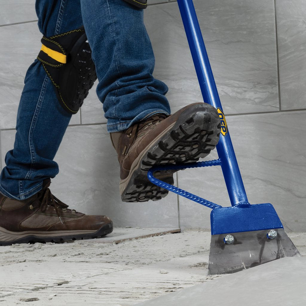 Close-up of QEP floor scraper blade in use removing tile with visible debris lift