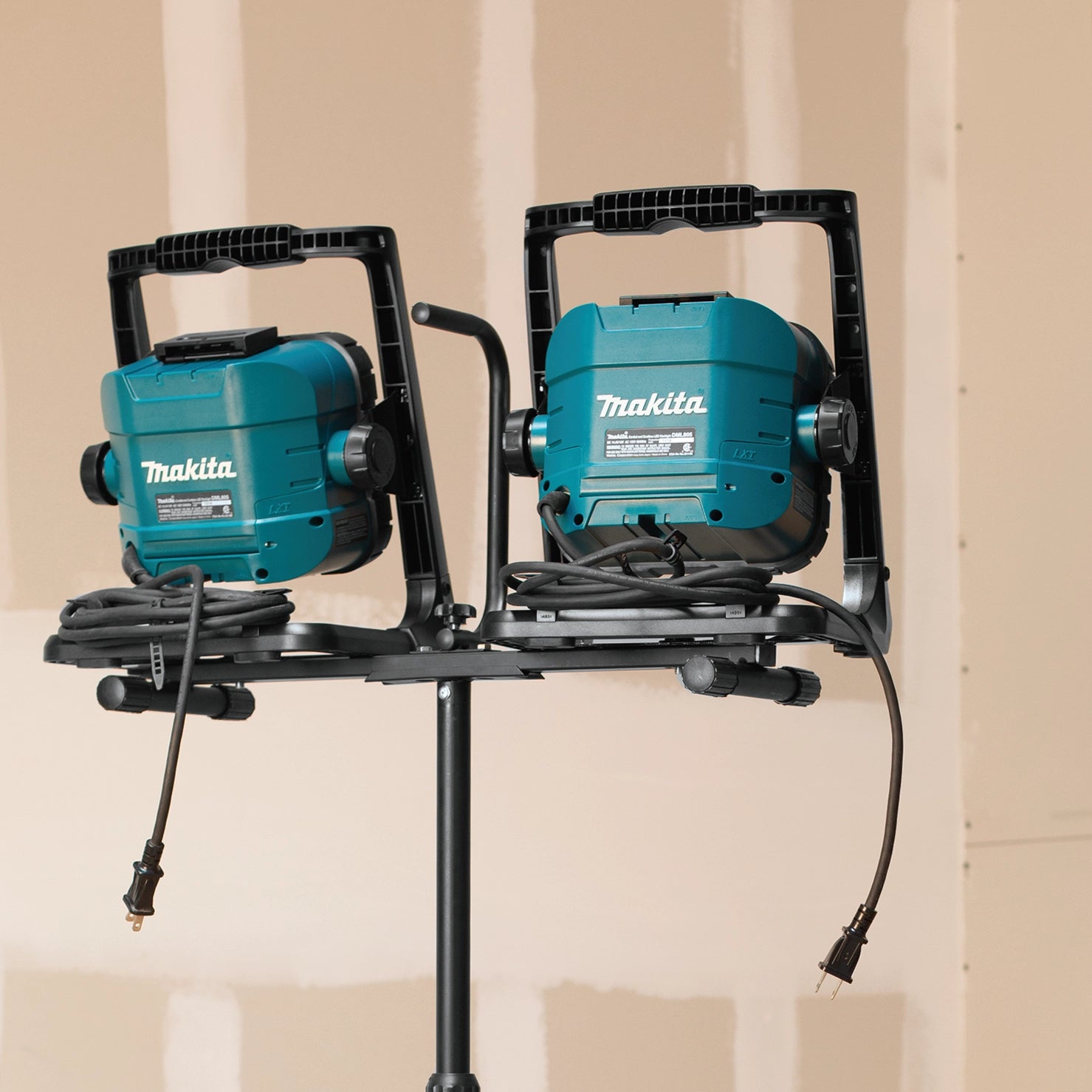 rear view of two makita led work lights on stand showing cord and battery setups

