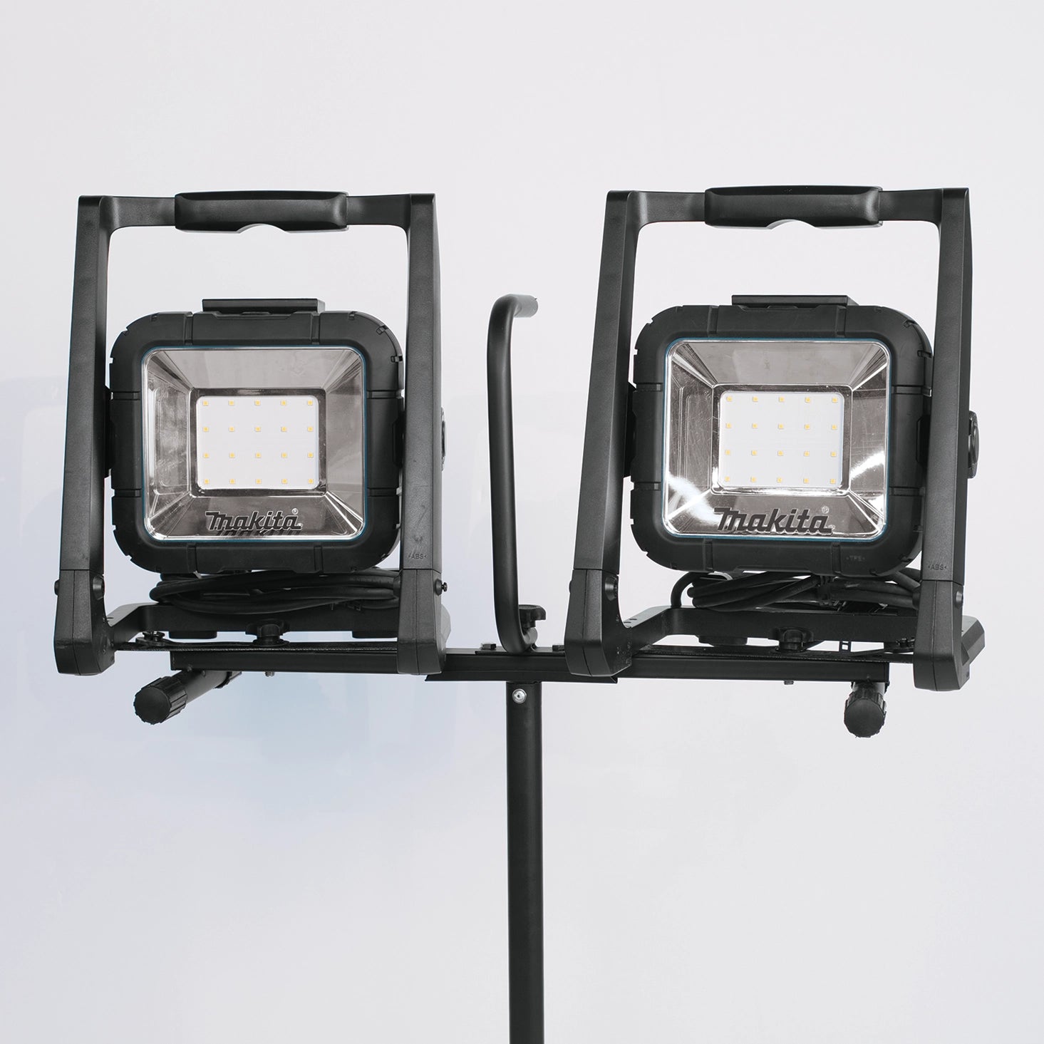 two makita led work lights mounted side by side on job site stand
