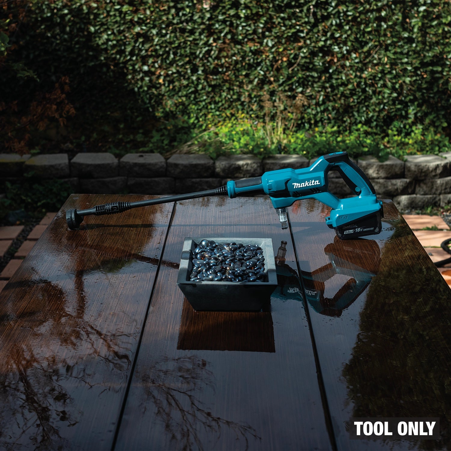 Blue Makita power tool on a wooden surface with a container of screws, outdoor setting.
