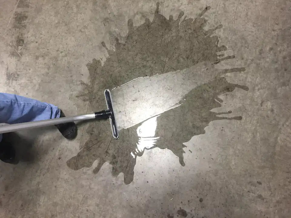 CenTec 14" squeegee tool in use, removing standing water from a concrete floor.