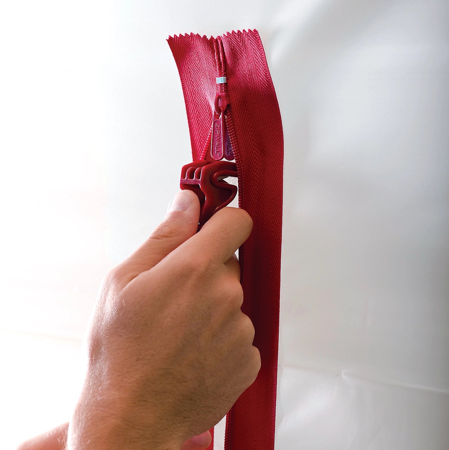 Close-up of ZipWall HDAZ12 zipper teeth and adhesive backing on plastic barrier
