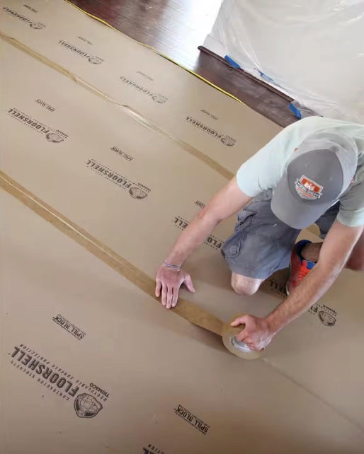 Close-up of tape installation over Floor Shell board by contractor in protective setup
