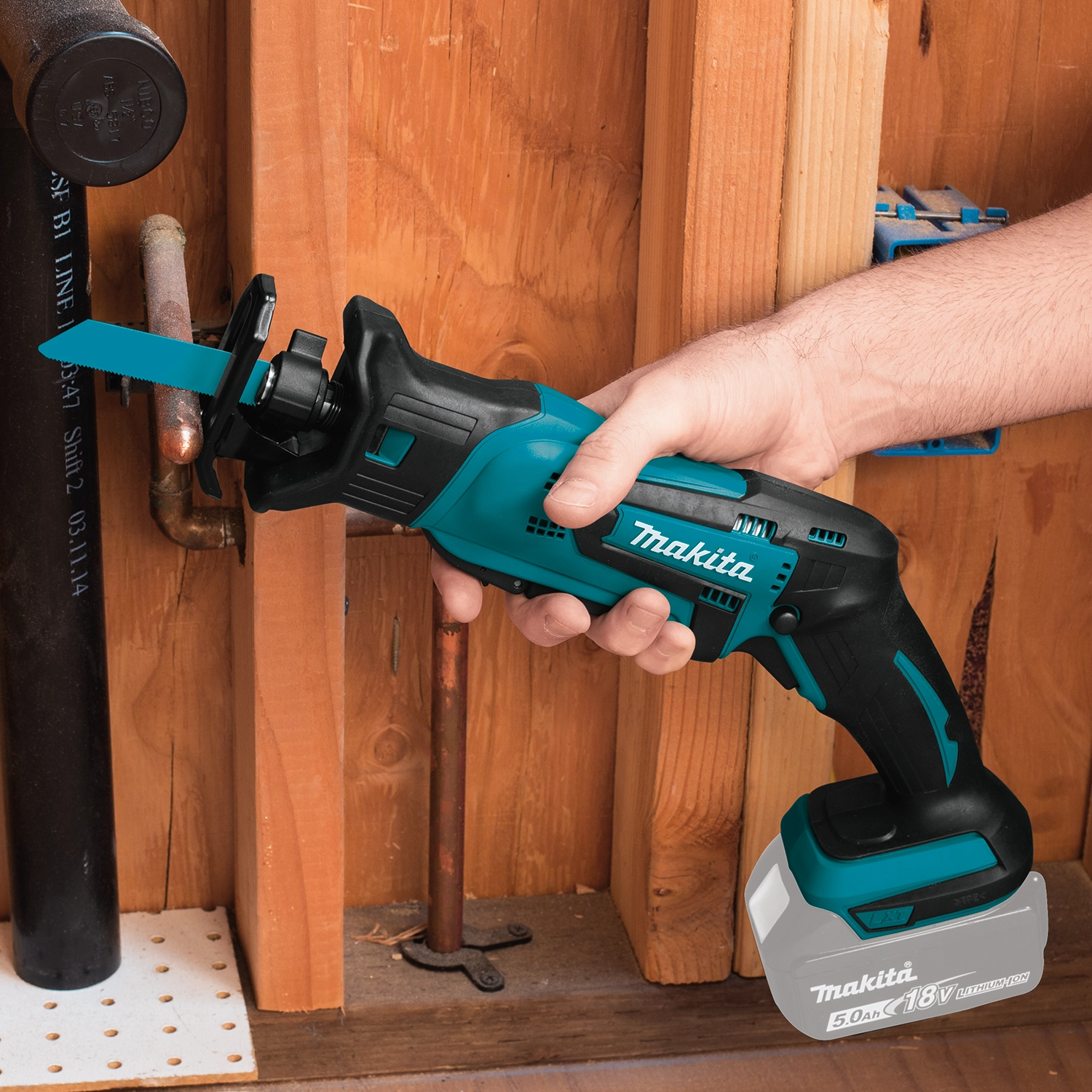 makita compact recipro saw cutting wood on construction site with debris in background
