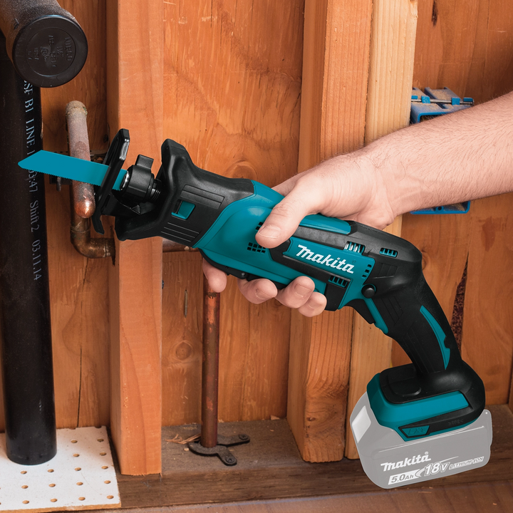 makita compact recipro saw cutting wood on construction site with debris in background
