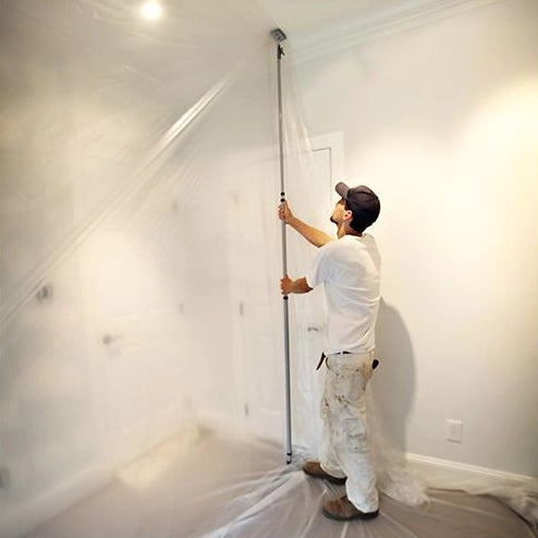 Contractor extending E-Z UP pole vertically to fit ceiling height for dust barrier setup
