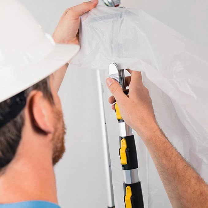 Contractor attaching plastic sheeting to E-Z UP dust containment pole during setup
