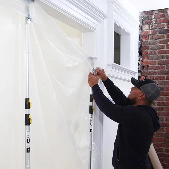 Contractor securing edge of plastic sheet to E-Z UP pole at doorway opening

