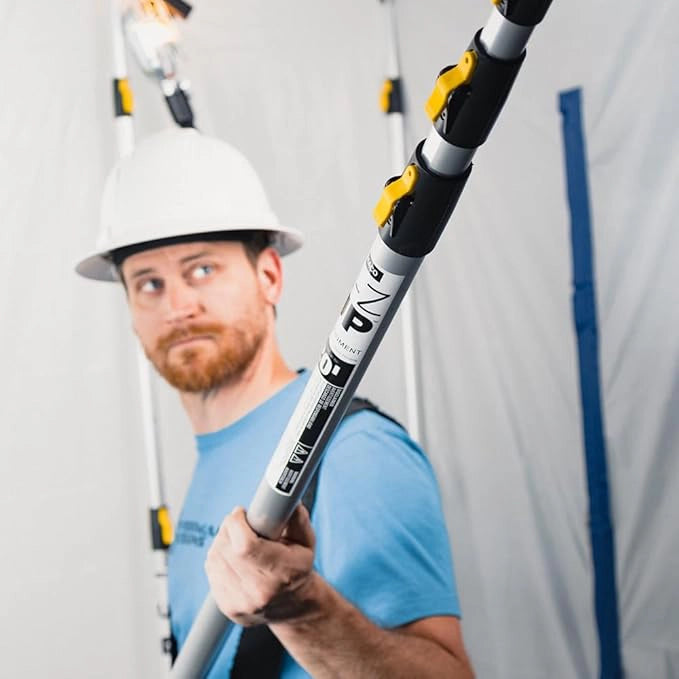 Construction worker holding fully collapsed E-Z UP pole before extending for use
