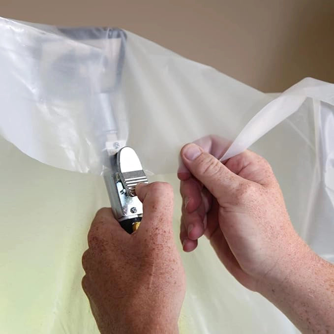 Close-up of hands securing plastic sheeting to E-Z UP pole using quick-clip system
