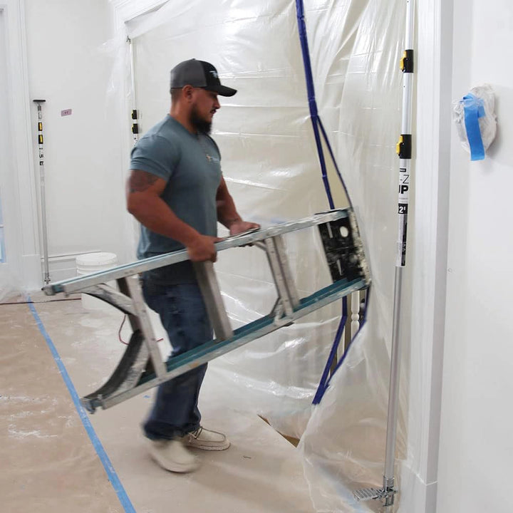 Worker walking through doorway with ladder under plastic sheeting supported by E-Z UP poles
