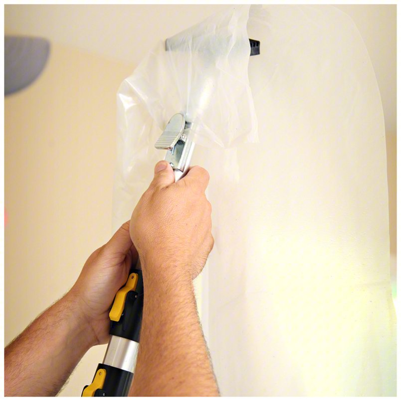 Contractor using E-Z UP pole to push plastic sheeting upward and clip it into place
