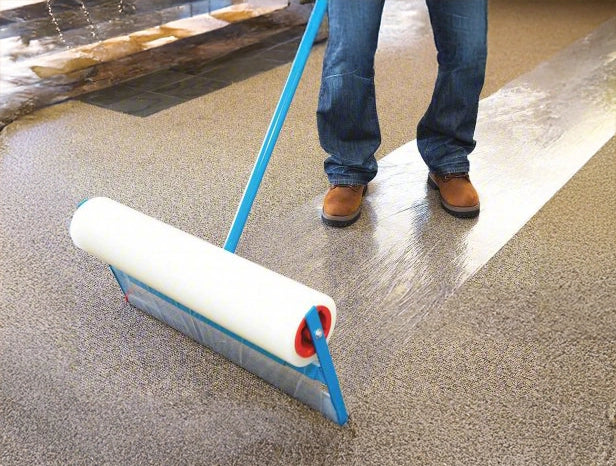 Protective film rolled out across floor with Trimaco Applicator resting on surface
