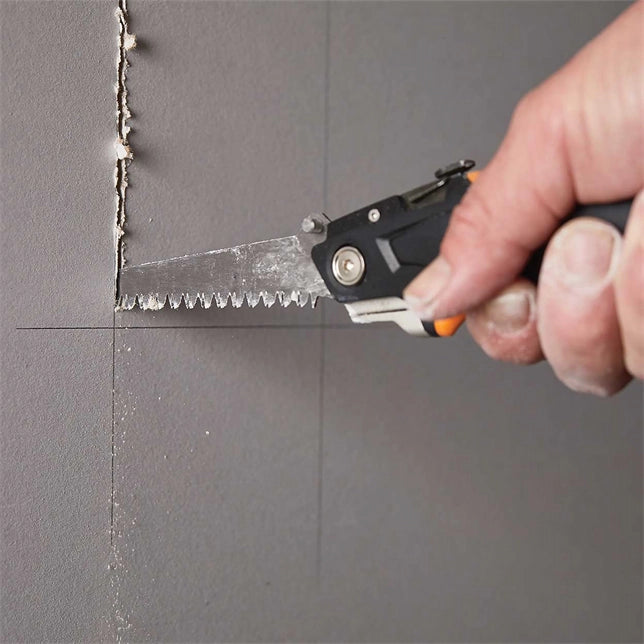 Worker using Fiskars Drywaller’s Knife/Saw to cut through drywall sheet
