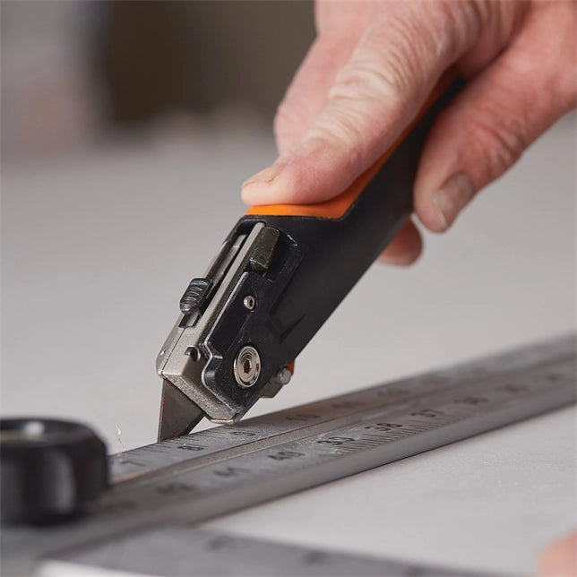 Contractor using box cutter function of Fiskars Drywaller’s Knife/Saw on drywall surface

