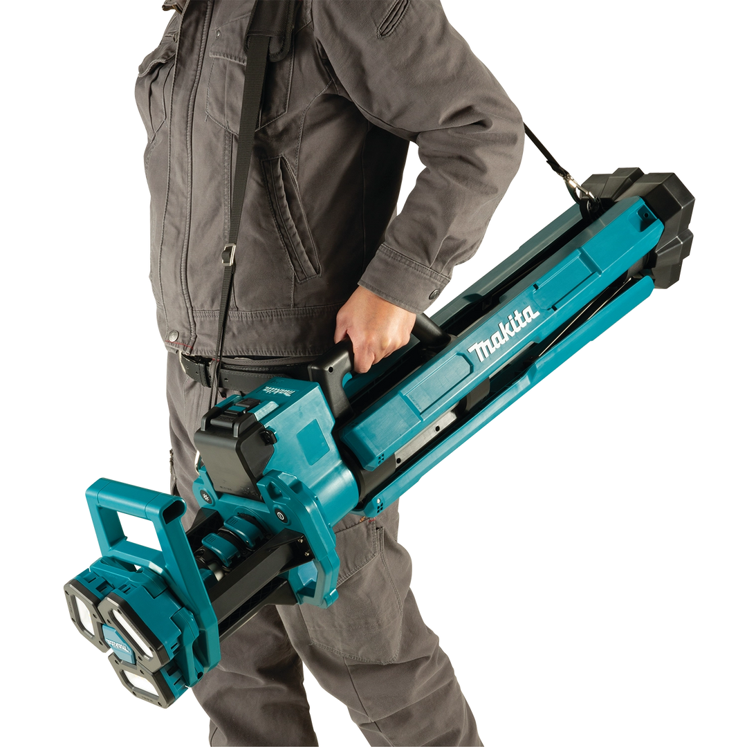 worker holding makita tower work light while adjusting height or positioning
