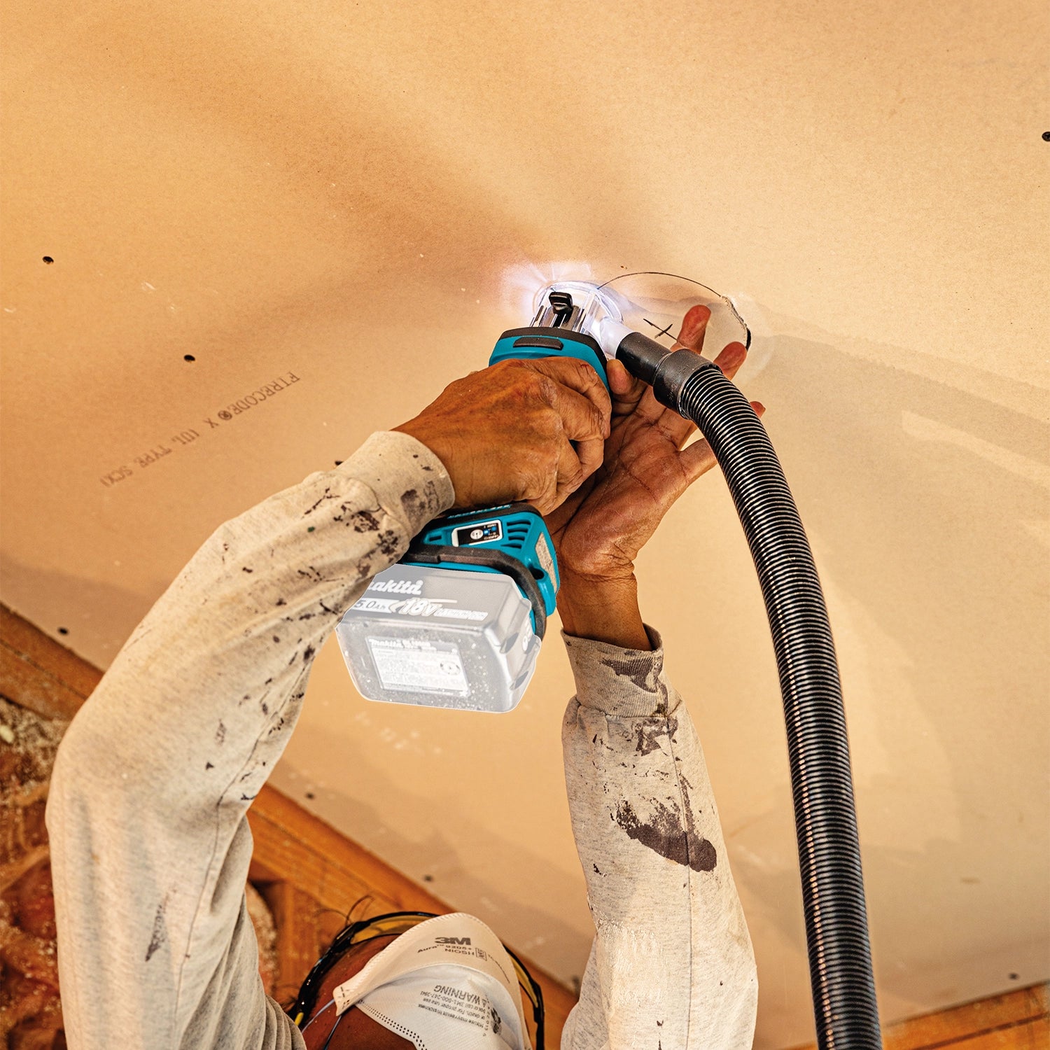 makita xoc02z cut-out tool in use overhead for drywall installation above head
