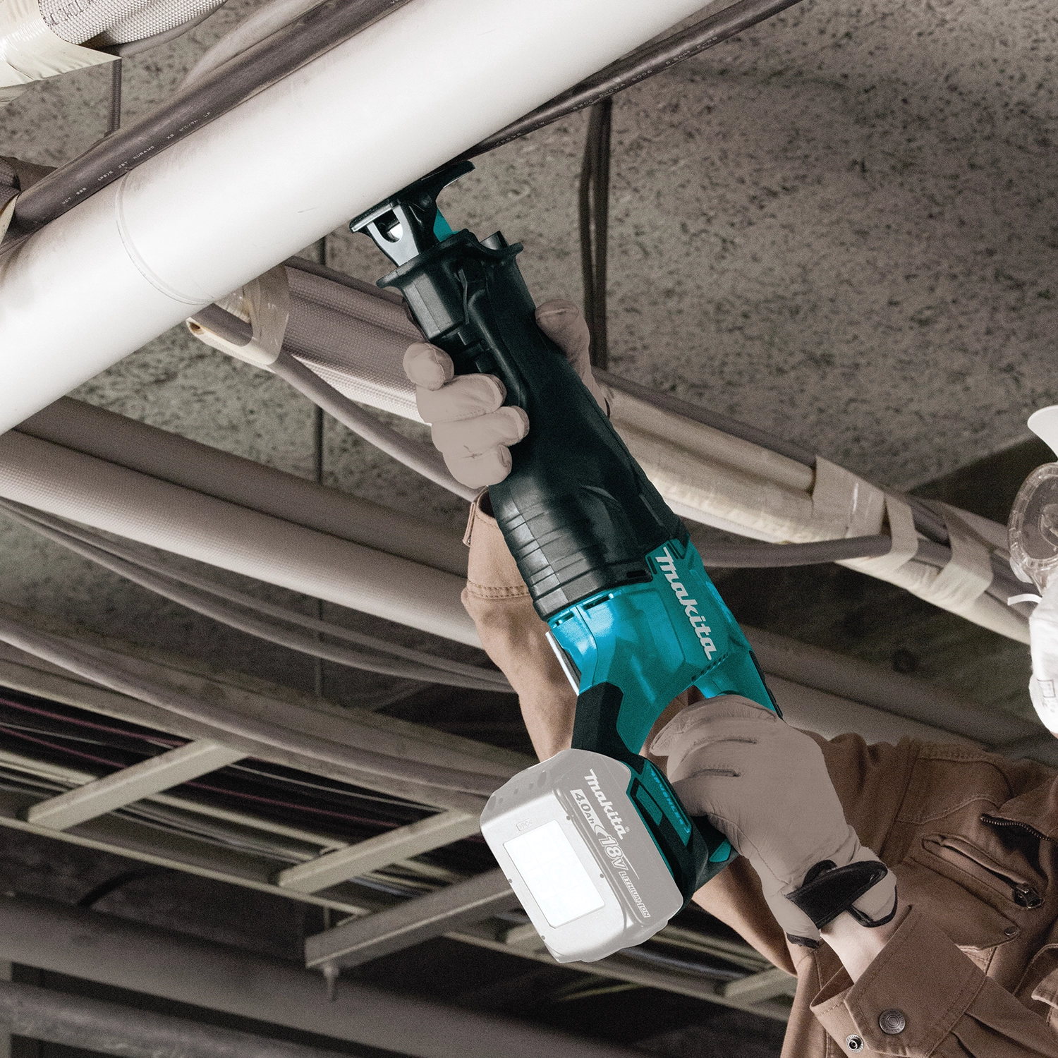 makita 18v lxt reciprocating saw in action cutting metal pipe
