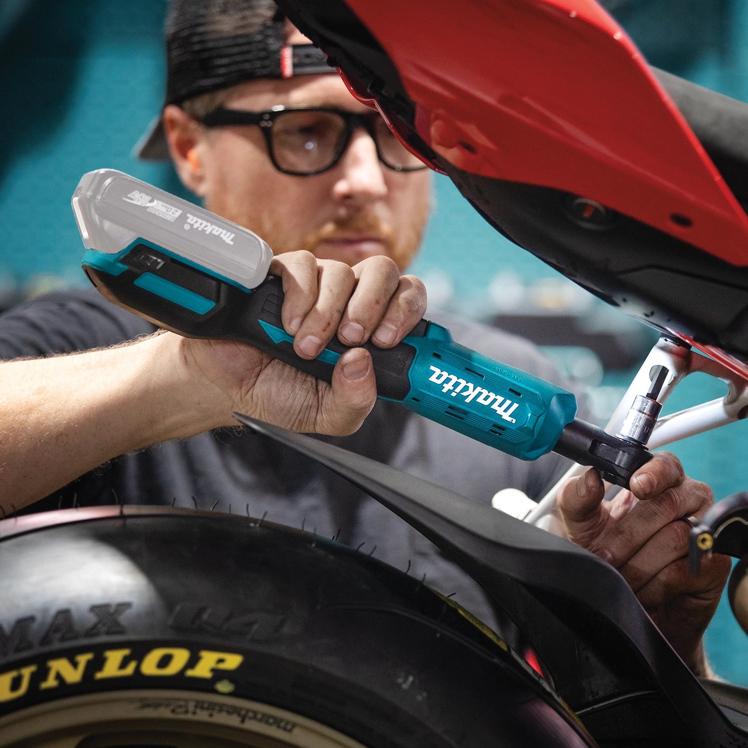 mechanic using makita cordless ratchet under vehicle in garage setting
