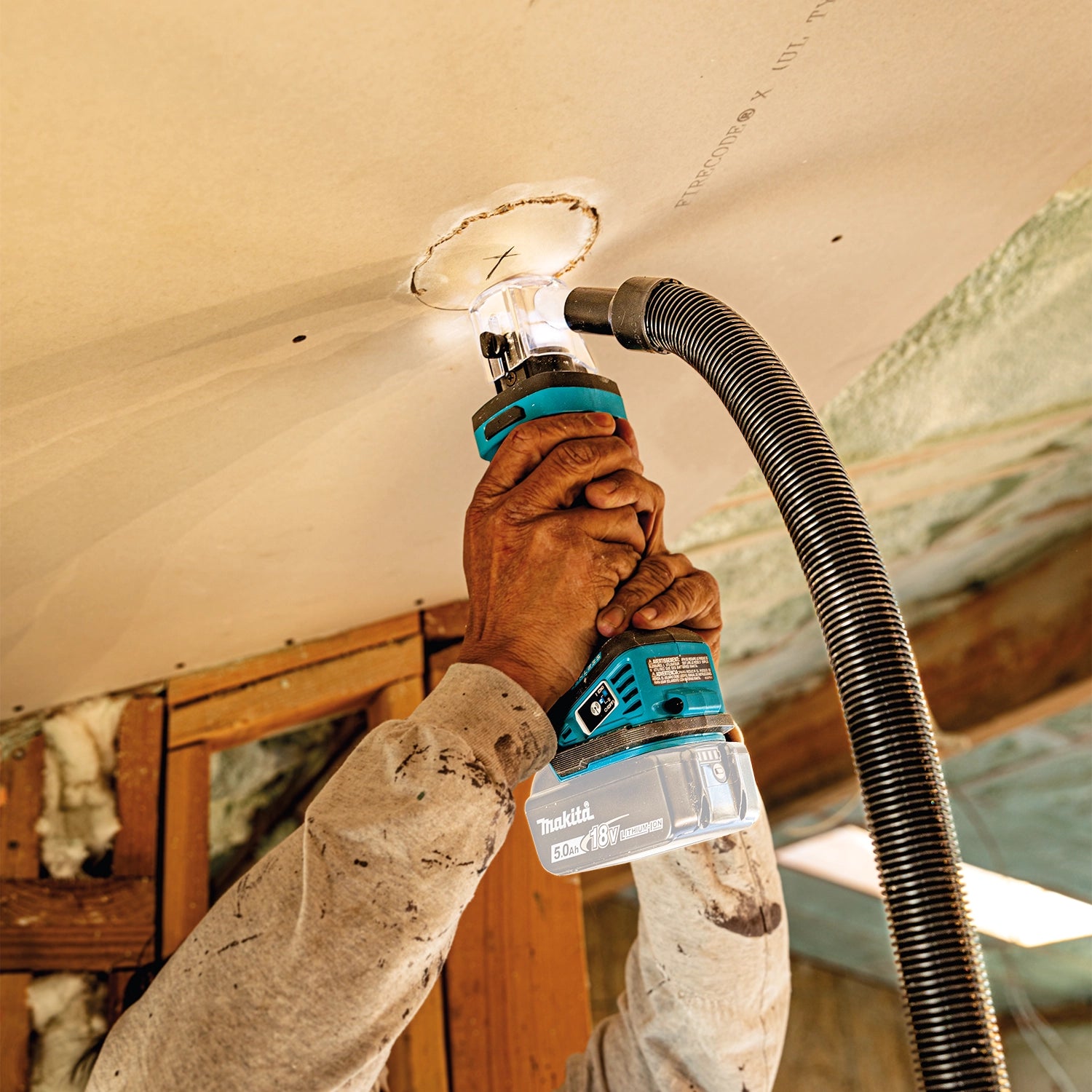 makita 18v lxt cut-out tool in use on ceiling for electrical access point installation
