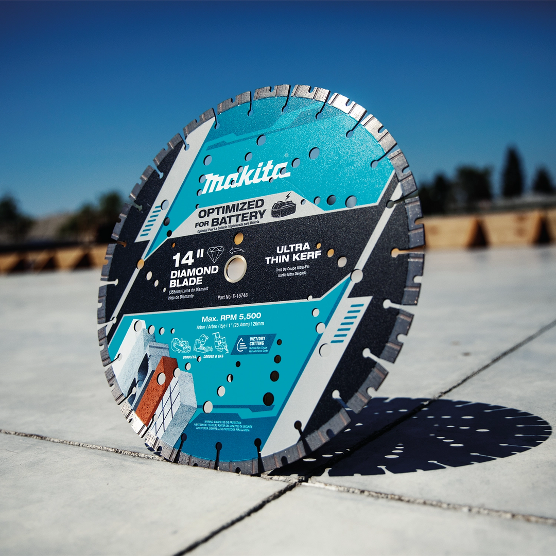 Makita 14" diamond blade cutting into a concrete slab on a job site with visible dust
