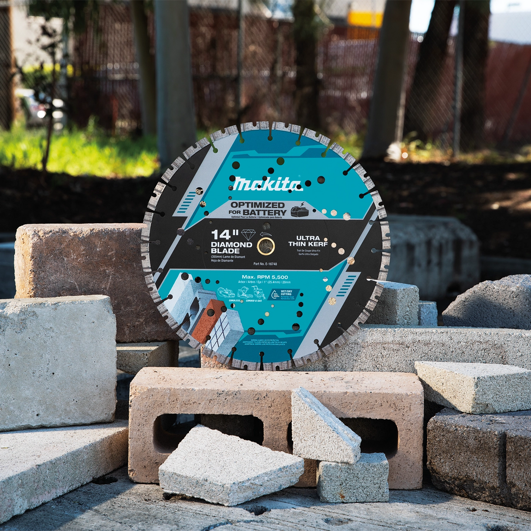 Makita 14" blade in use outdoors cutting through stone block on a landscaping job site
