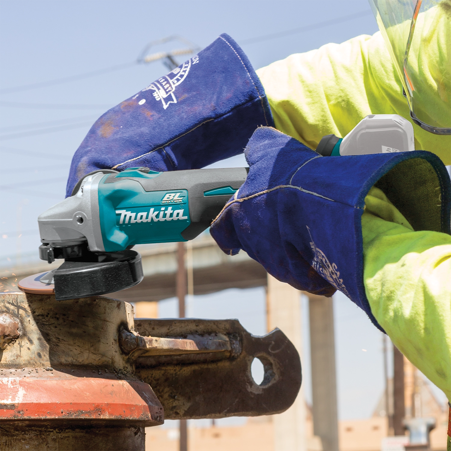 Worker grinding metal with Makita 18V grinder on job site

