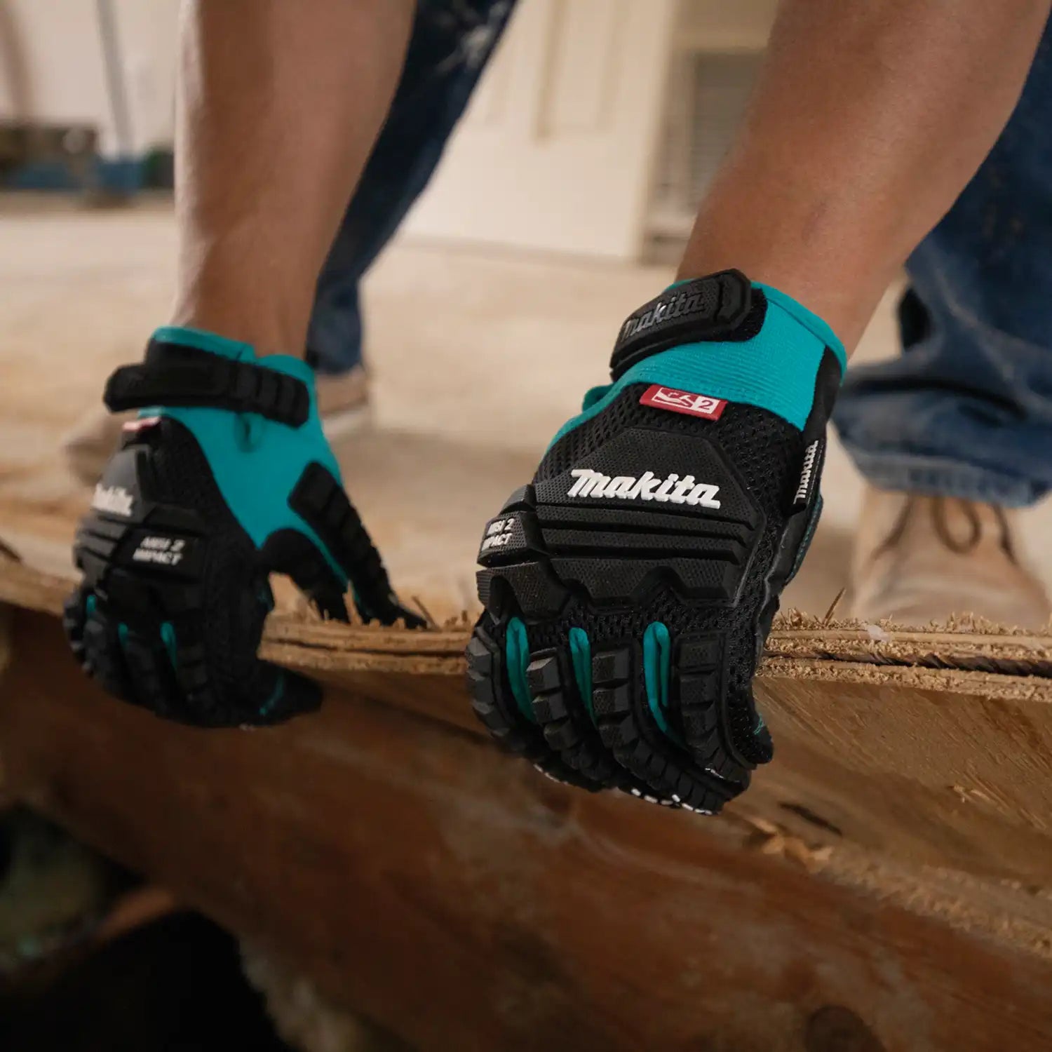 Worker wearing Makita gloves while kneeling and removing flooring debris
