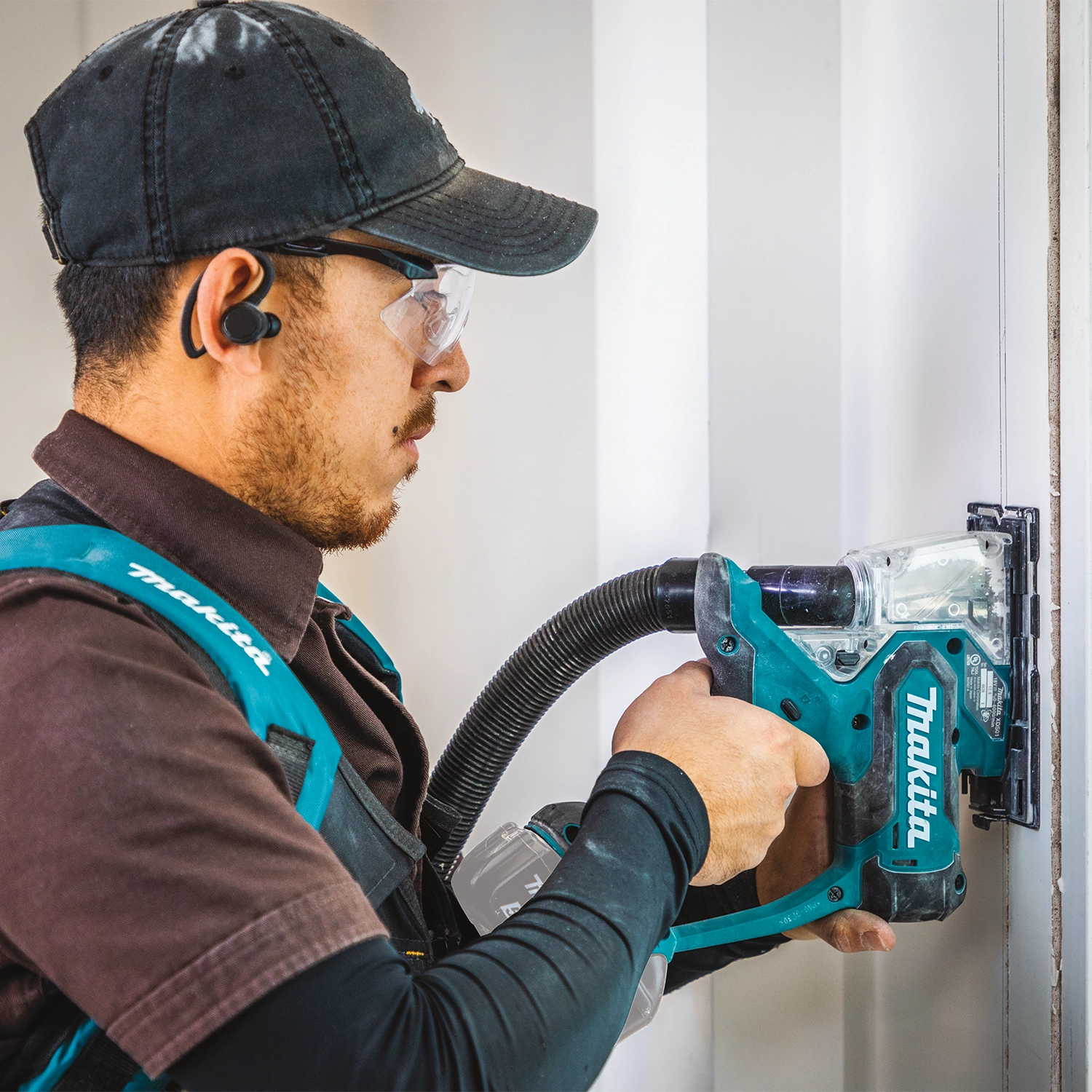 Makita saw cutting sheetrock panel with dust vacuum setup
