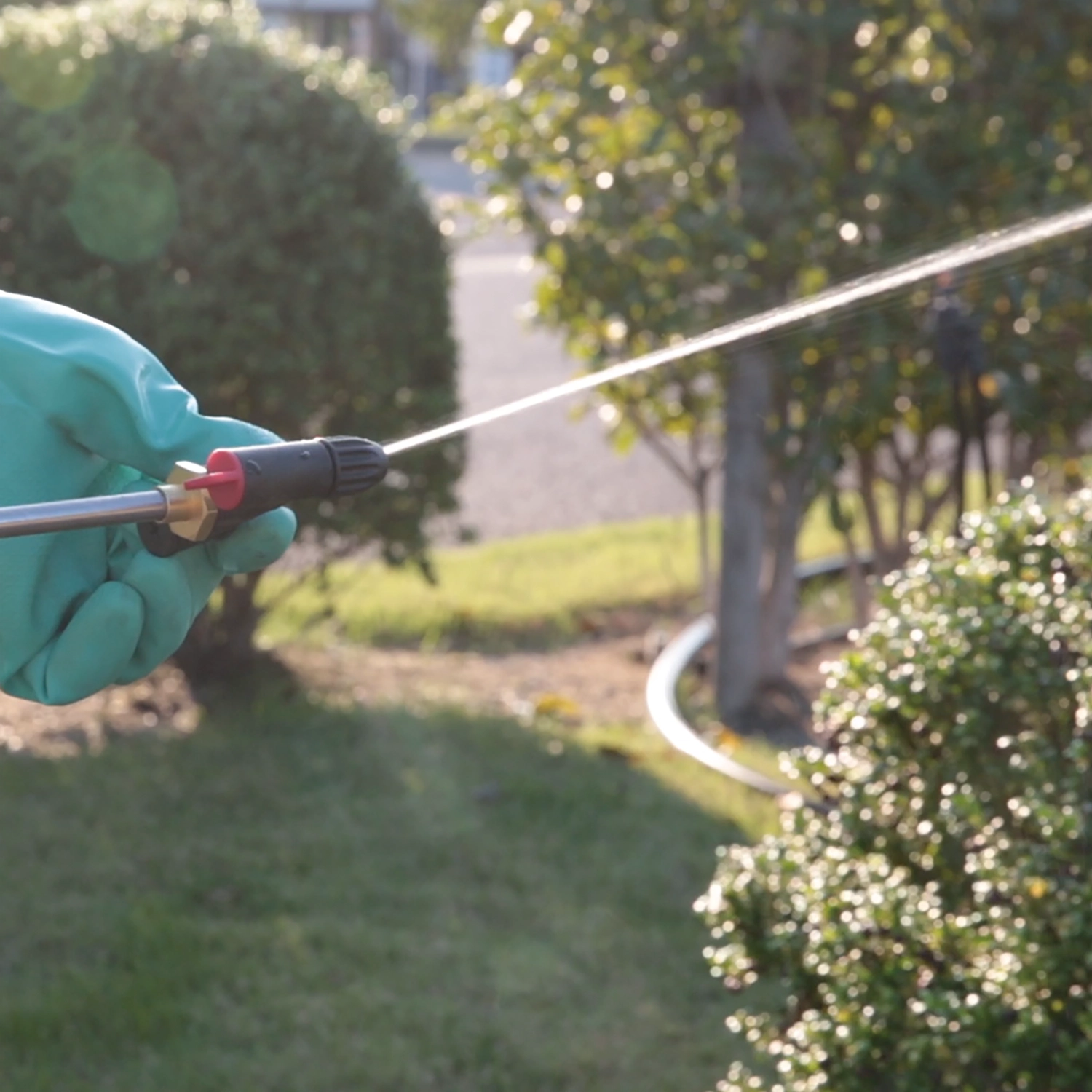 Sprayer in use applying herbicide to plants in landscaped area
