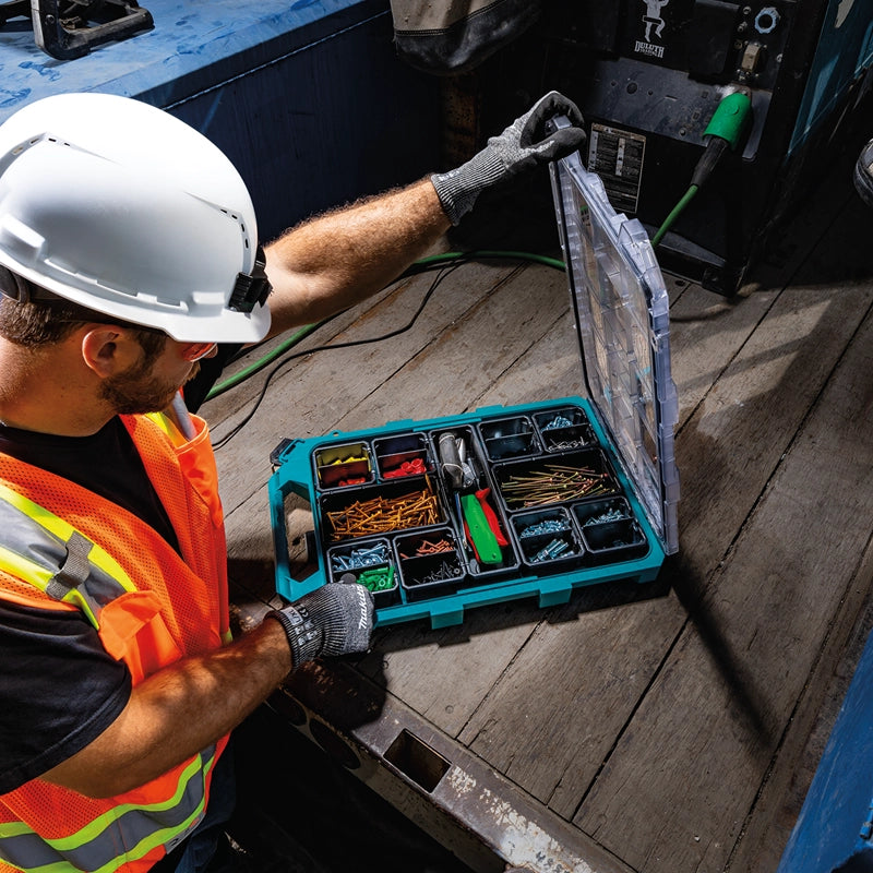 Construction worker organizing tools and fasteners in Makita T-90059 MAKTRAK™ Organizer on jobsite floor


