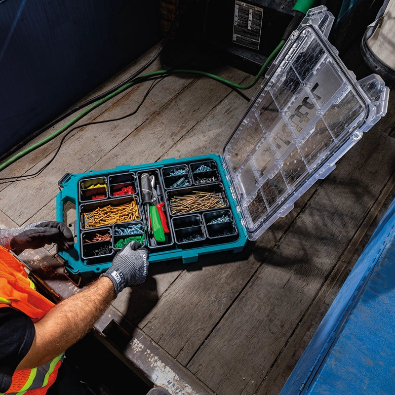 Worker organizing screws and tools inside an open Makita T-90059 MAKTRAK Low Profile Organizer on a wooden workbench in a jobsite truck.

