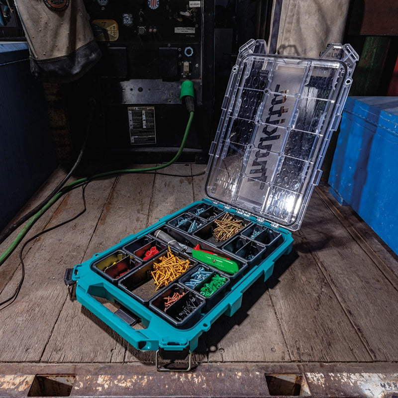 Makita T-90059 MAKTRAK™ organizer open on a work truck bed, filled with screws, connectors, and hand tools at a jobsite.

