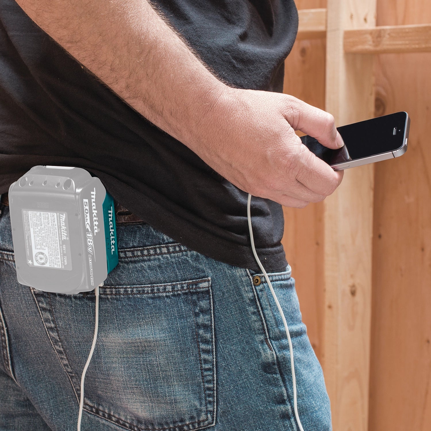 Smartphone charging on user’s hip from Makita USB adapter
