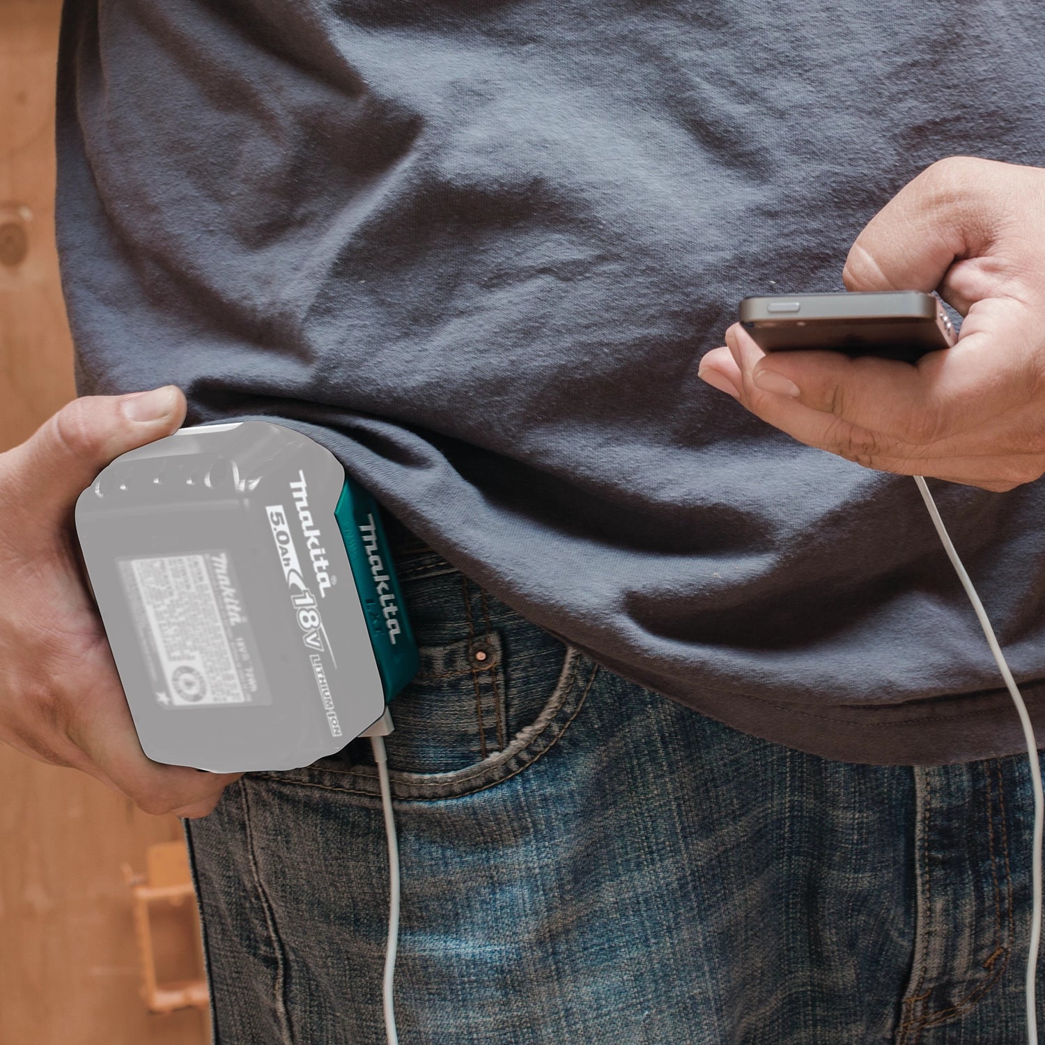 Makita USB power source clipped to hip charging a smartphone
