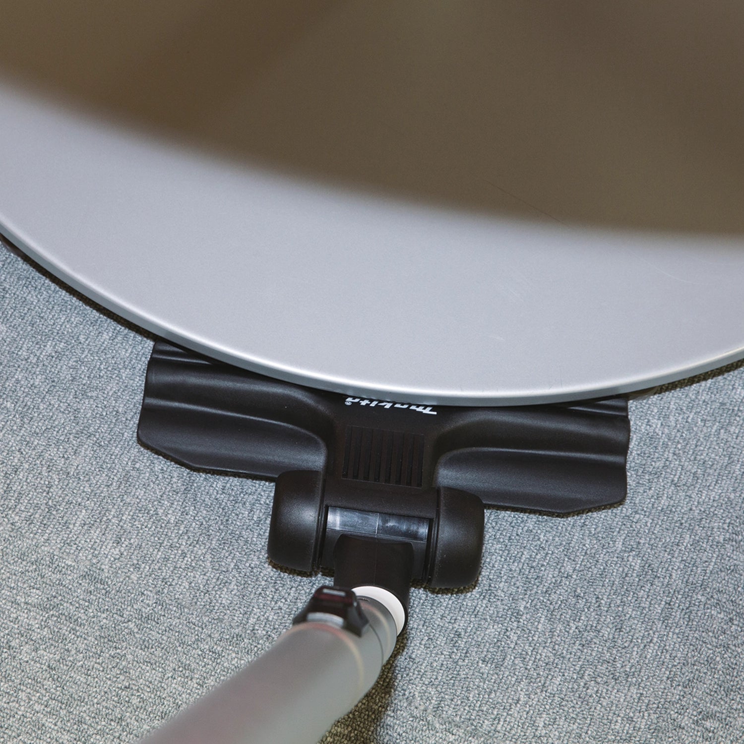 Vacuum wand fitting under office desk showing compact cleaning access
