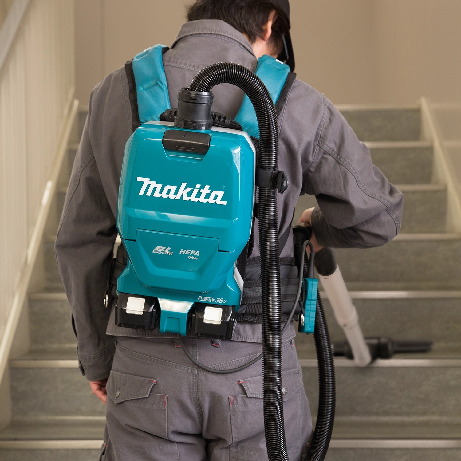 Worker wearing Makita HEPA vacuum strapped on for mobile use
