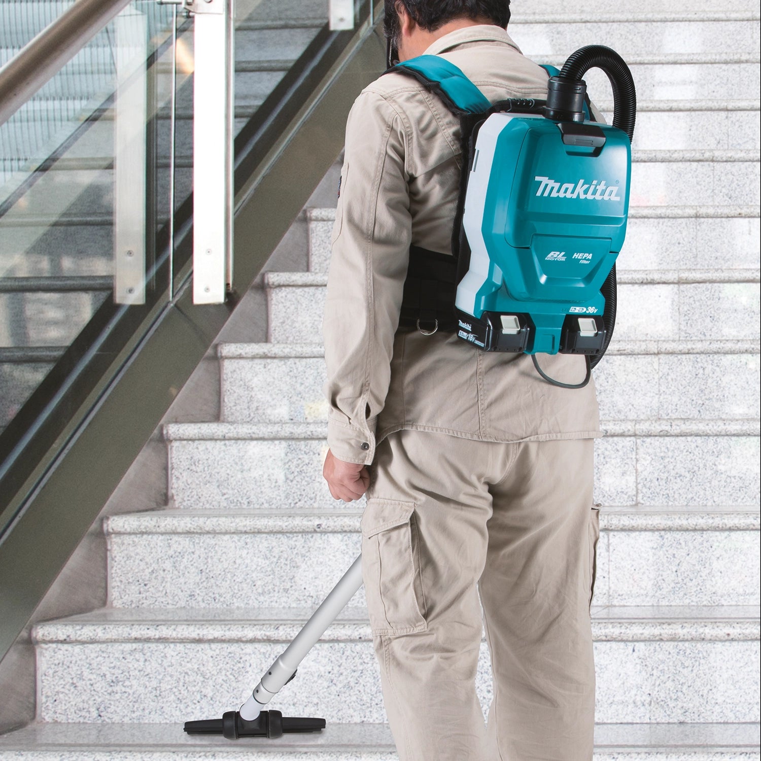 Makita vacuum user cleaning debris on stairway with hose extension
