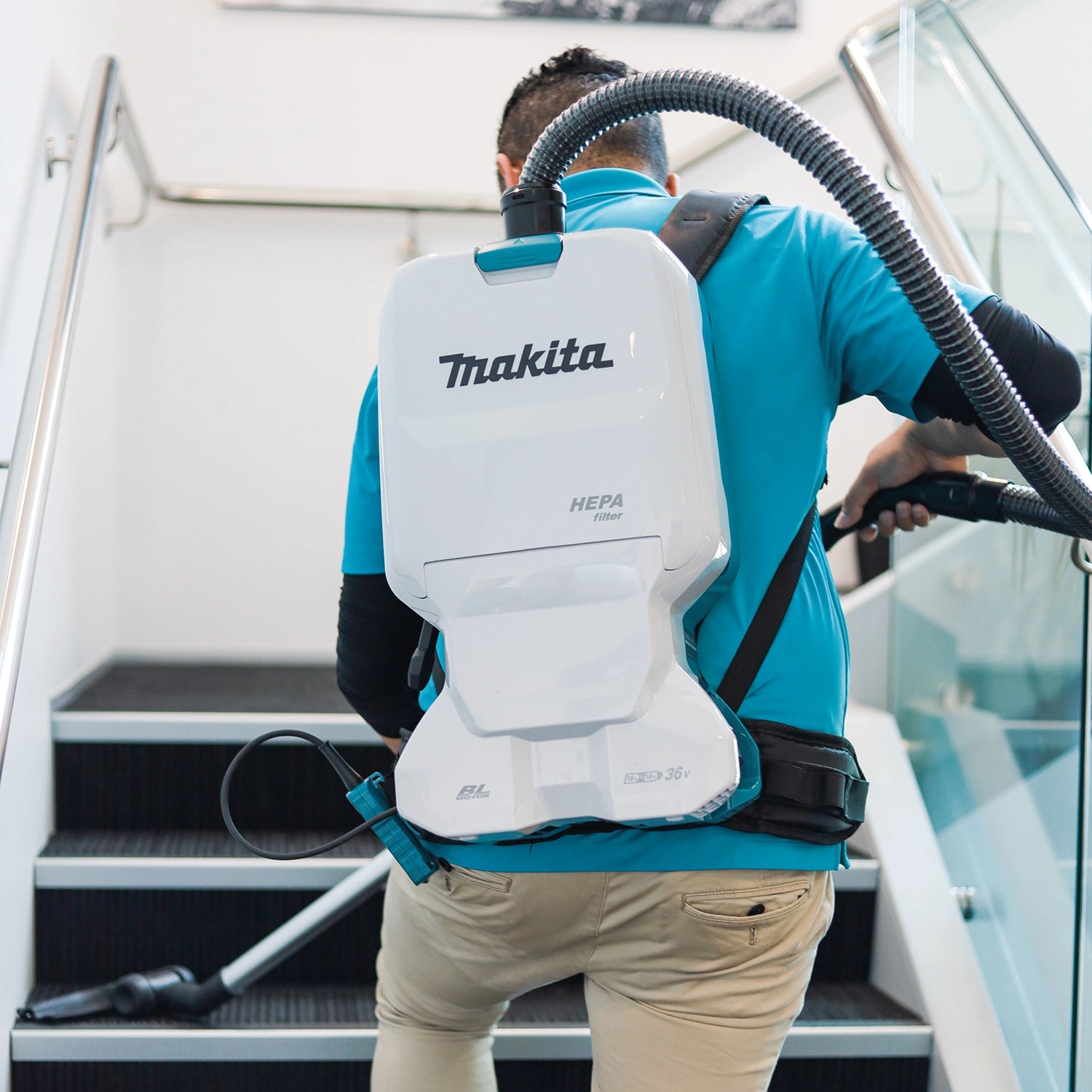 makita backpack vacuum being used to clean baseboards and tight corners
