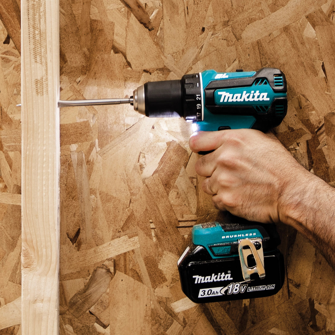 Makita driver-drill actively drilling into wood surface
