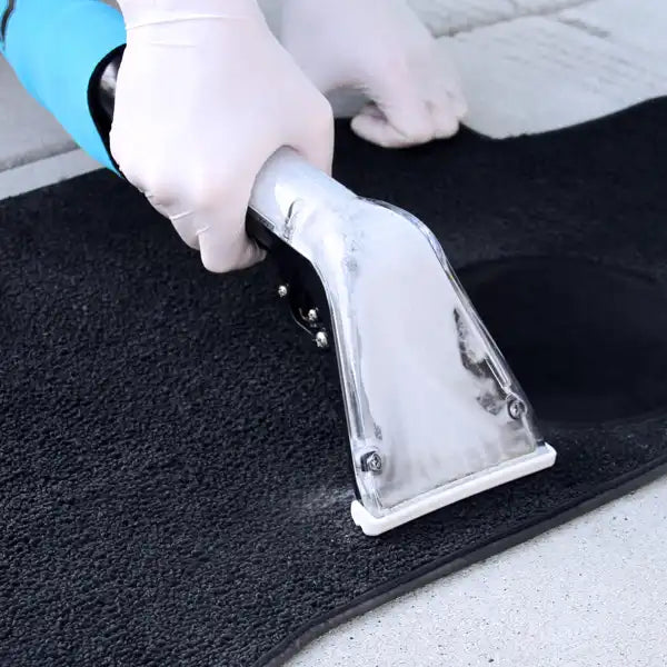 Technician using the Mytee 8400P Air Lite Upholstery Tool to clean a carpeted floor mat with gloved hands