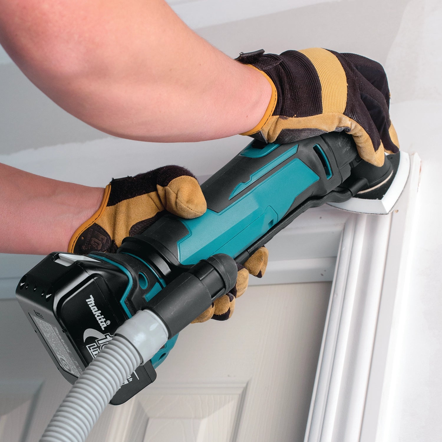 makita multi-tool with dust extractor used on jobsite during material removal
