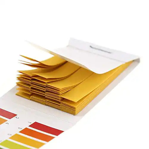 Close-up stack of pH strips fanned out inside the booklet