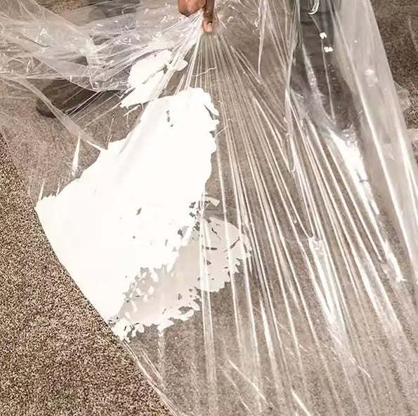 Presto carpet film being peeled to reveal clean carpet under dried paint splatter
